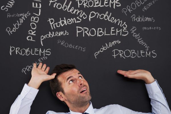 Businessman bending under stack of problems